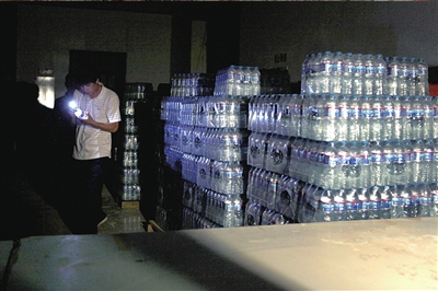 一名執法人員在一儲藏仿冒飲料的倉庫中檢查。